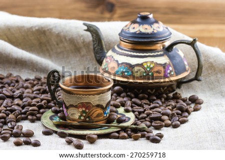 Old vintage painted coffee set copper cup and teapot with heap of roasted coffee beans on sackcloth