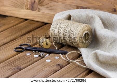 Close-up view of old sewing kit: scissors, twine, thread, buttons, sackcloth on wooden background