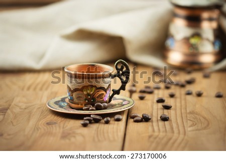 Traditional Turkish coffee set: vintage copper cup with coffee turk and roasted coffee beans on wooden table