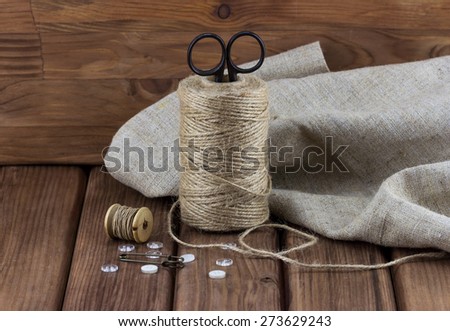 Close-up view of old sewing kit: scissors, twine, thread, buttons, sackcloth on wooden background