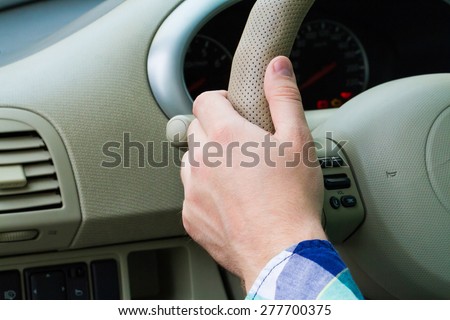 Close-up view of male hand on the steering wheel of a car