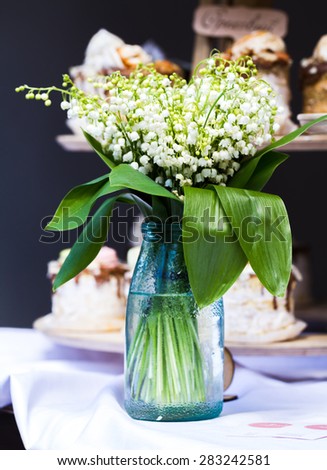 Glass vase with lilies of the valley flowers on wooden table