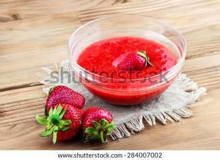 Top view of strawberry mash in a glass with fresh strawberries on wooden background