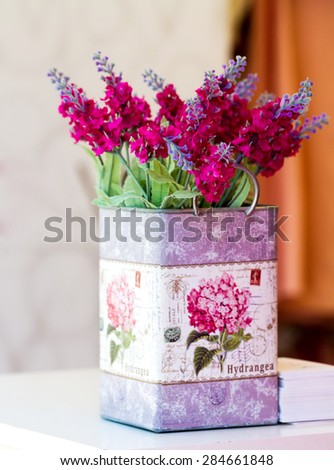 Beautiful red flowers in decorative metal vase on white wooden table