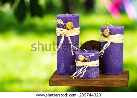 Handmade purple wedding candles with yellow bow and ribbon on wooden table