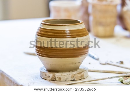 Crude clay pot on a wooden plate in outdoor workshop