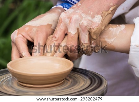 Woman with help of master hands working on pottery wheel and making clay plate