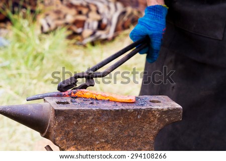 Blacksmith lays down a hot iron on anvil for forging