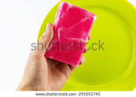 Hand with red sponge washing green plate isolated on white background