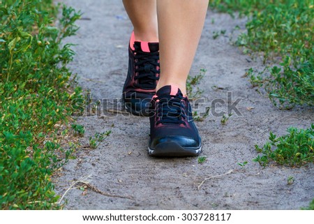 Running fitness concept. Close-up view of walking or running woman shoes in use on road in the park