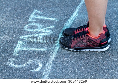 Kiev, Ukraine - August 12, 2015: Sport woman in Reebok sneakers getting ready to run near the start line