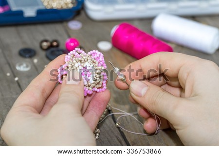 Making of handmade jewellery. Box with beads, spool of threads, needle on wooden background. Handmade accessories