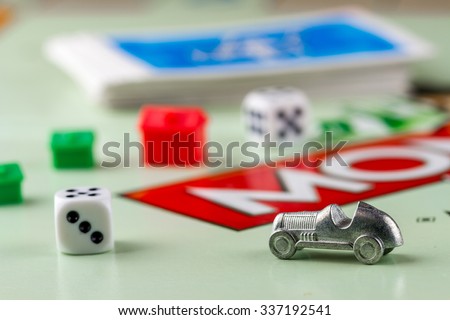 Ukraine, Kiev - October 29, 2015: Close-up view of Monopoly game pieces: car, pair of dice, houses, cards on board. Focus on the toy car