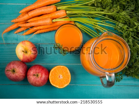 Homemade natural carrot juice in glass on rustic blue wooden table in background