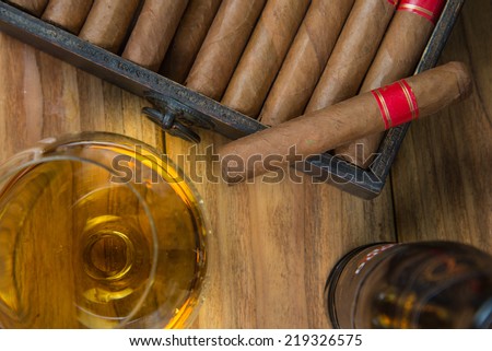 Cuban cigars and Rum or other alcohol in glass on table top view with vintage wooden background