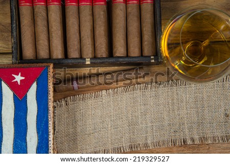 Cuban cigars and Rum or other alcohol in glass on table top view with vintage wooden background and copy space