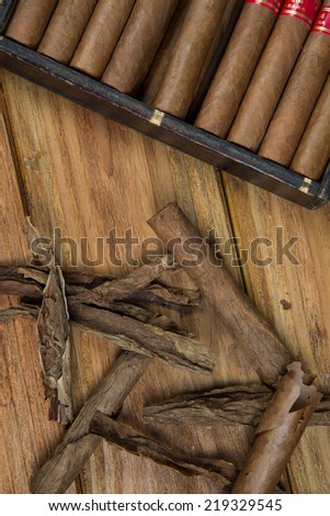 Cuban cigars and Rum or other alcohol in glass on table top view with vintage wooden background