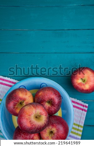 Farm fresh organic red autumn apples on colorful kitchen cloth on wooden retro blue table in background