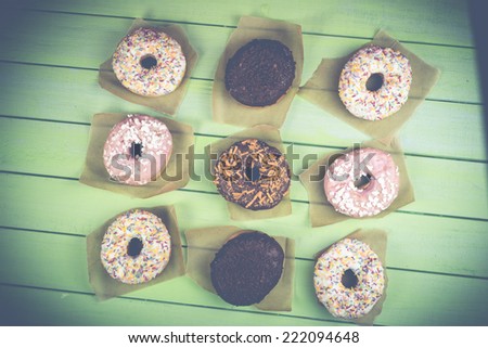 Colorful donuts on wooden table in retro style filter