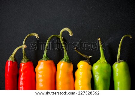 many vibrant colors on peppers on black slate background