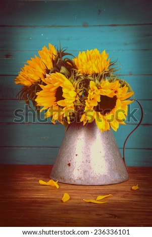 Fresh sunflower flowers in rustic antique vase on wooden table and rustic background