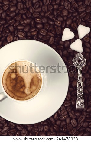overhead view on cup of espresso coffee  and roasted beans with sugar and silver spoon