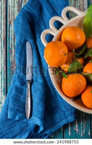 Market fresh clementines in rustic bowl, on wooden table with cloth