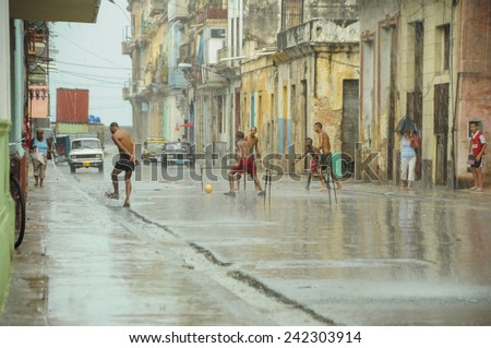 HAVANA, CUBA - MAY 31, 2013 Local Cuban kids play football or soccer on street in Havana, Cuba while tropical storm approching with heavy rain but very hot air.