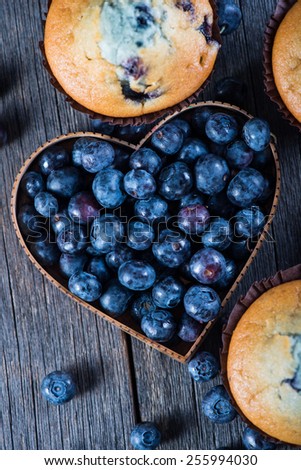 Blueberry muffins and fruit heart on wooden table from above