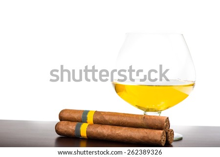 Cuban cigar and glass with rum or cognac isolated on wooden bar