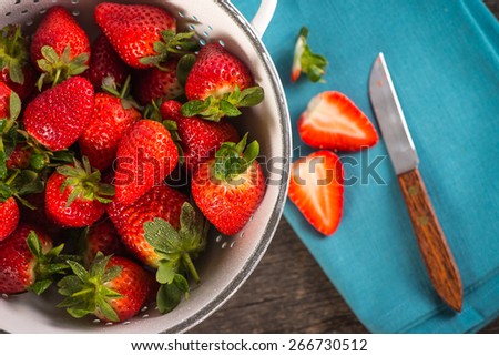 Fresh just clean wet strawberries in rustic colander from above