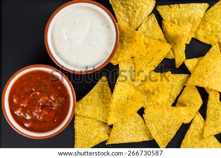 mexican street food nachos  with salsa and cream dip on black background