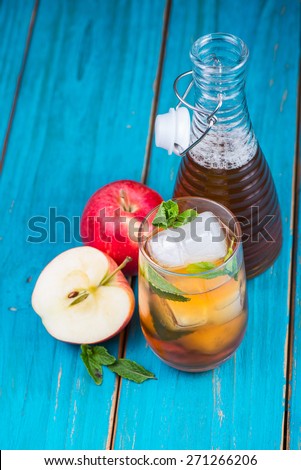 Fresh pressed apple juice with mint leaves and ice on wooden table