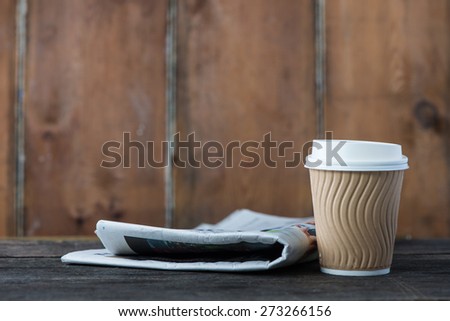 Take away coffee and newspaper on wooden background