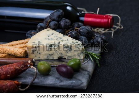 Marble board with cheese selection, wine and grapes on dark background from above