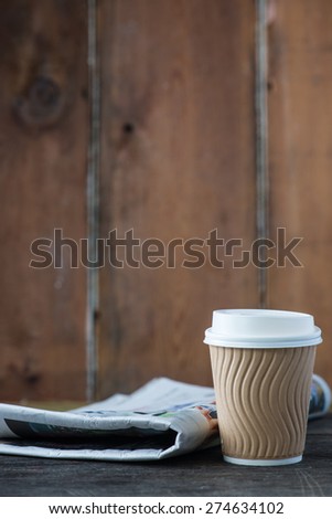 Take away coffee and newspaper on wooden background