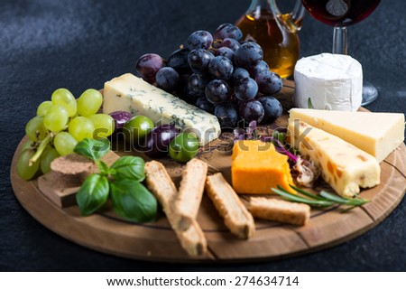Cheese board with fresh grapes,herbs and olives, red wine