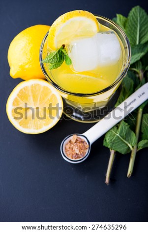 Refreshing lemonade with fresh citrus , mint and ice in glass on black background