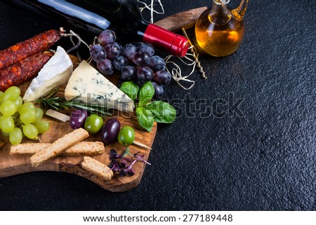 Tapas board with cheese,olives,grapes and red wine,food border background