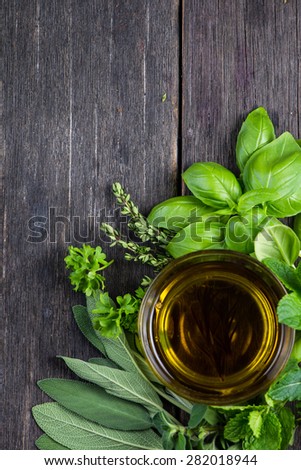 Fresh herbs from garden with olive oil, on wooden rustic background