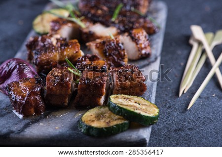 Grilled pork belly slices on marble board with skewers from above