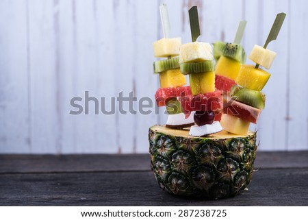 Healthy party snack, exotic fruits on skewers, on wooden table