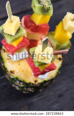 Healthy party snack, exotic fruits on skewers, on wooden table