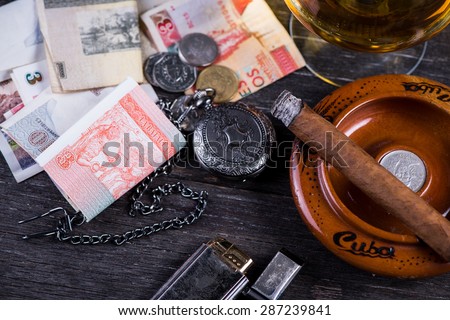 Cuban domino game on table with cigar,rum, pessos notes and pocket watch, from above