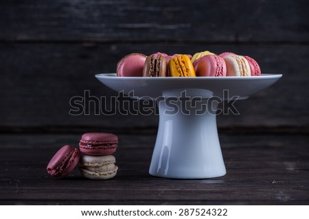 Colorful french macaroons on platter and wooden background with copy space