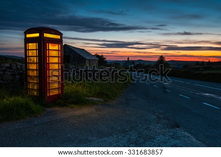 Iconic red phone booth in English countryside at night