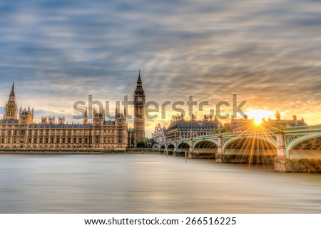 Big Ben, Parliament and Westminster Bridge viewed from South Bank of the River Thames at sunset. The setting sun\'s rays splash across Westminster Bridge.