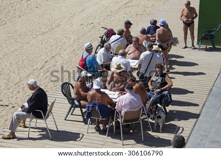 BARCELONA - MAY 23, 2015: Men play domino at tables on the beach in Barcelona, Spain on May 23, 2015.