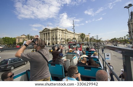 Barcelona, Spain - May 25, 2015: Tourists take pictures on a double decker bus touring around the city of Barcelona, Spain on May 25, 2015.