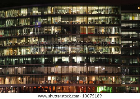 Office tower with lighted windows in late evening, people working late